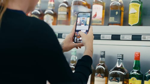 Customer scanning a product QR code in the aisle to add it to a virtual shopping cart